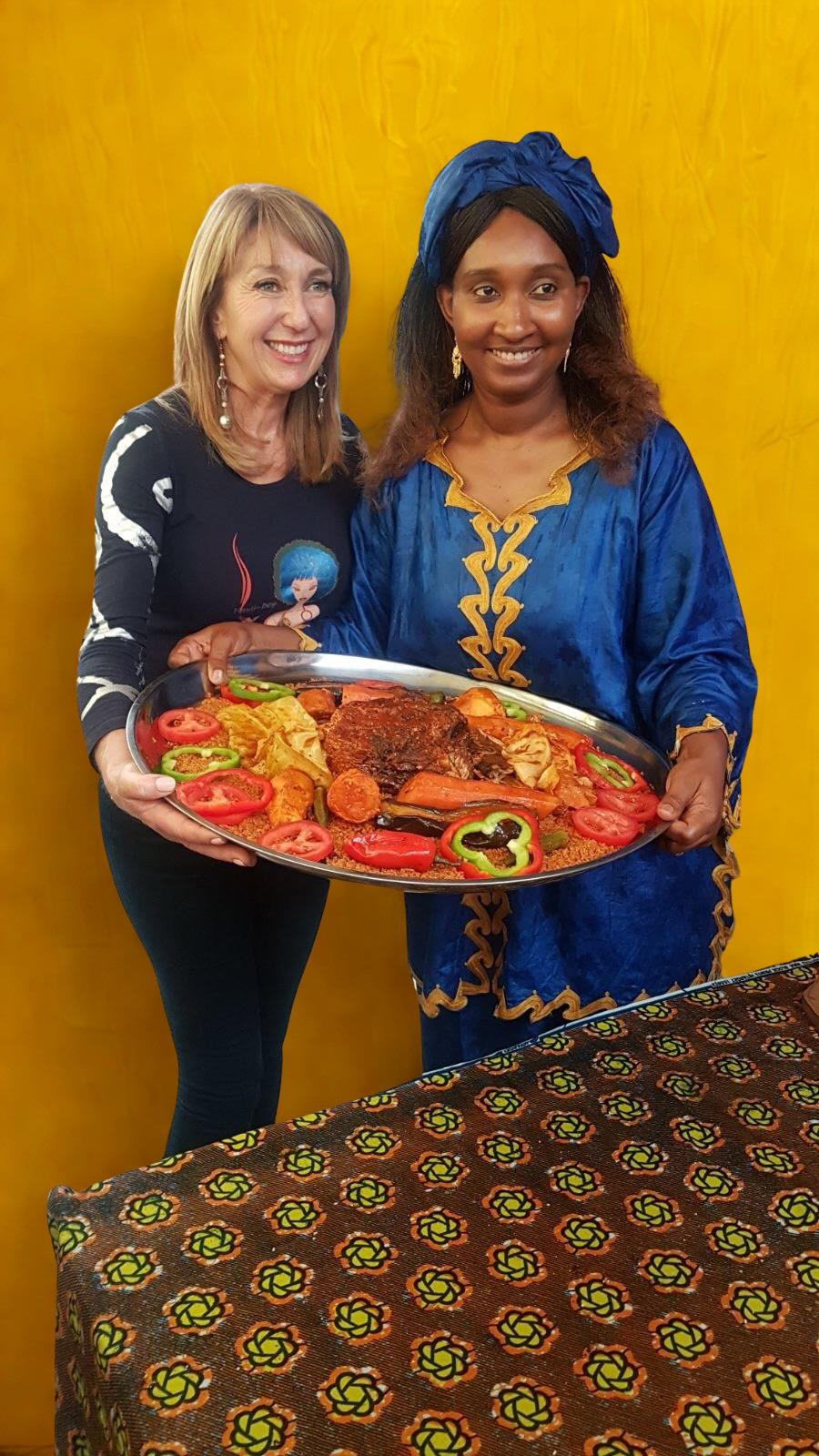 Aissatou Ba with a guest holding a traditional Senegalese platter