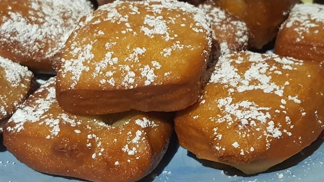Golden Senegalese beignets dusted with powdered sugar